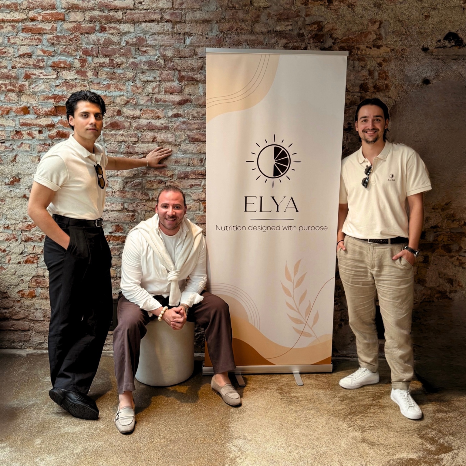 The ELYA team beside the ELYA brand banner